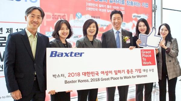 Baxter employees standing with great place to work for woman banner